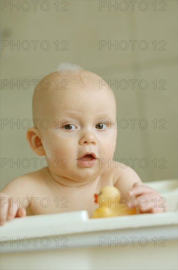 Baby in a bath with foam on his head