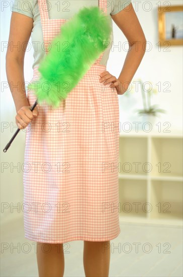 Housewife wearing an apron and holding a feather duster