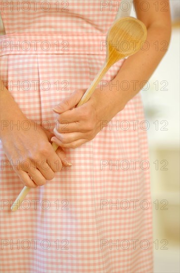 Housewife wearing an apron and holding a wooden spoon