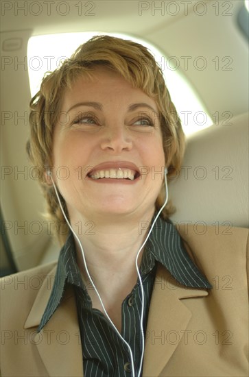 Business woman wearing headphones in a car