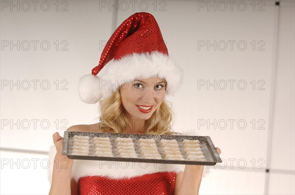 Sexy Miss Santa holding a baking tray with Christmas cookies