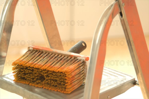 Large used paint brush lying on a ladder