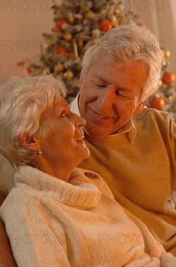 Mature couple in love sitting in front of a Christmas tree