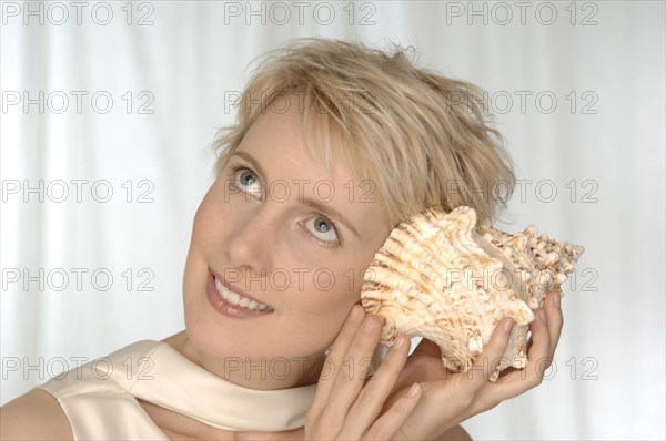 Young woman holding large shell to her ear
