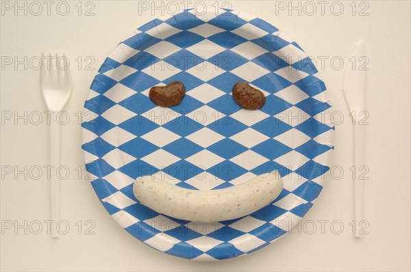 Weisswurst veal sausage making a face with mustard on a paper plate with the Bavarian diamond pattern