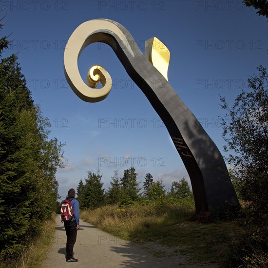 Hiker in front of the sculpture The Crook on the WaldSkulpturenWeg trail in Schanze