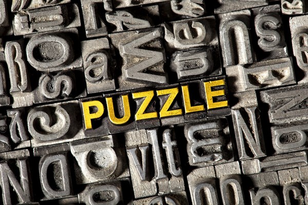 Old lead letters forming the word 'PUZZLE'
