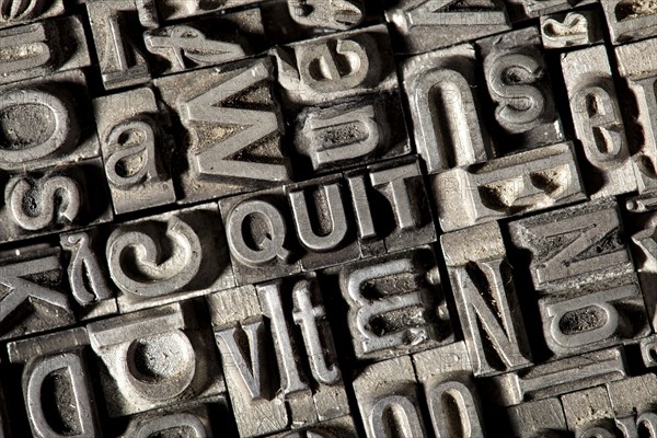 Old lead letters forming the word 'QUIT'