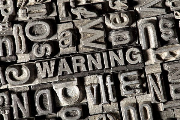 Old lead letters forming the word WARNING