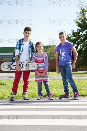 Children with a skateboard and carrying school bags on the way to school