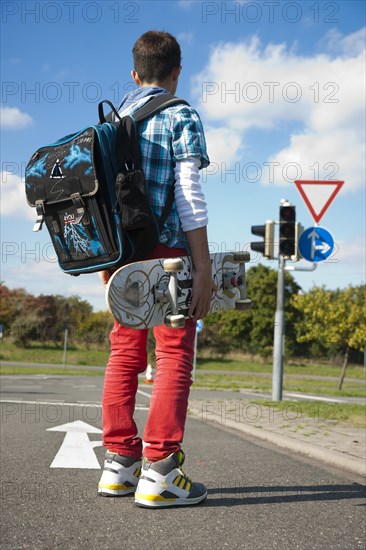 Boy with a school bag and a skateboard on a street