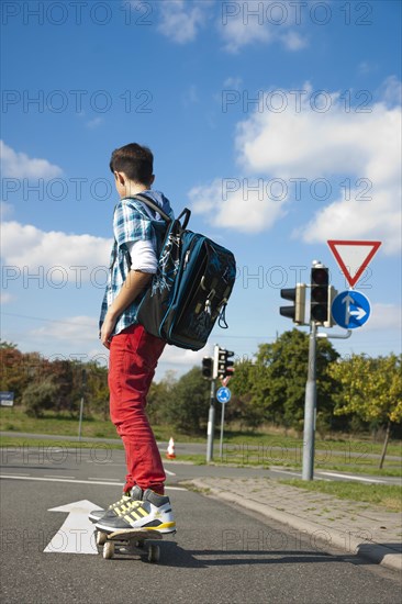 Boy with a school bag and a skateboard on a street