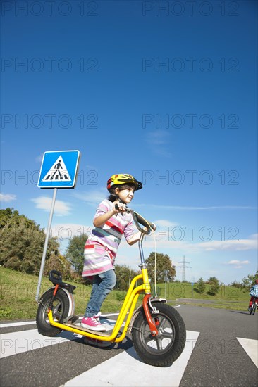 Girl crossing a zebra crossing with her scooter