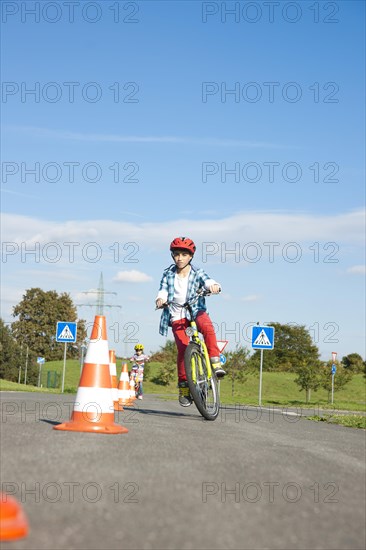 Child practicing to ride slalom on a bicycle at a traffic awareness course