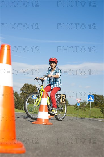 Child practicing to ride slalom on a bicycle at a traffic awareness course