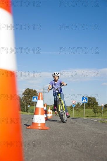 Child practicing to ride slalom on a bicycle at a traffic awareness course