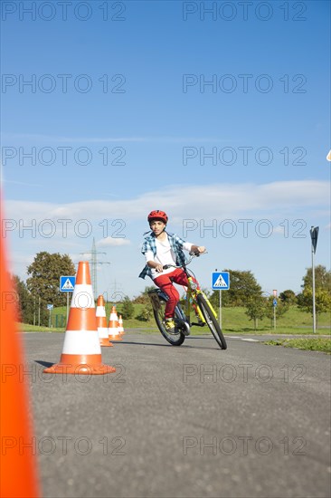 Child practicing to ride slalom on a bicycle at a traffic awareness course