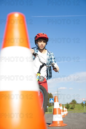 Child practicing to ride slalom on a bicycle at a traffic awareness course