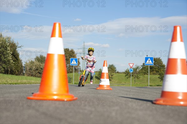 Girl practicing to ride slalom on a scooter at a traffic awareness course