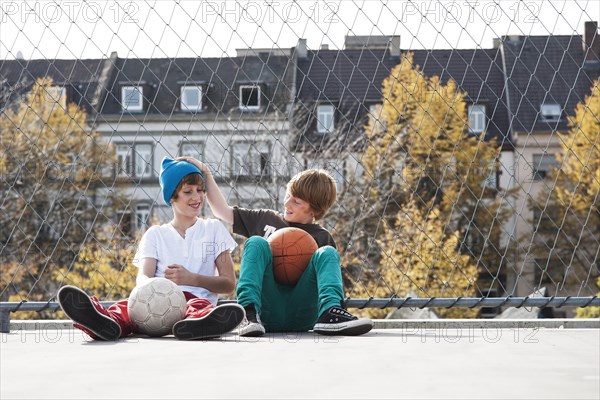 Two cool boys sitting with a basketball on a playground