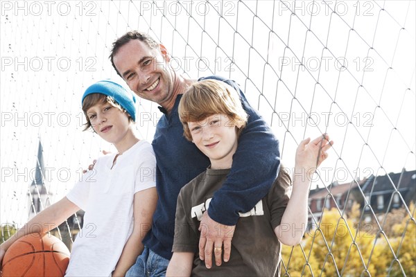 Two cool boys standing with their father on a playground