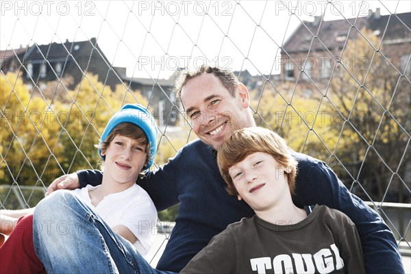 Two cool boys sitting with their father on a playground