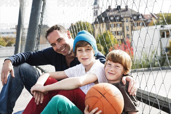 Two cool boys sitting with their father on a playground