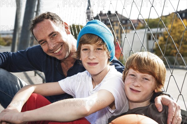 Two cool boys sitting with their father on a playground