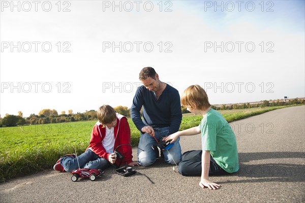 Father tinkering on a remote-controlled model car with his sons