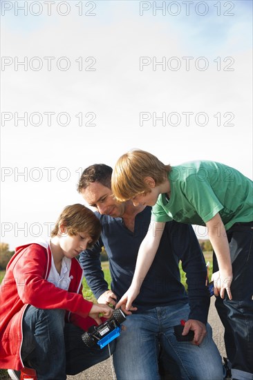 Father tinkering on a remote-controlled model car with his sons