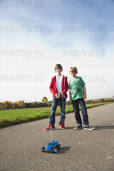 Two boys playing with a remote-controlled model car