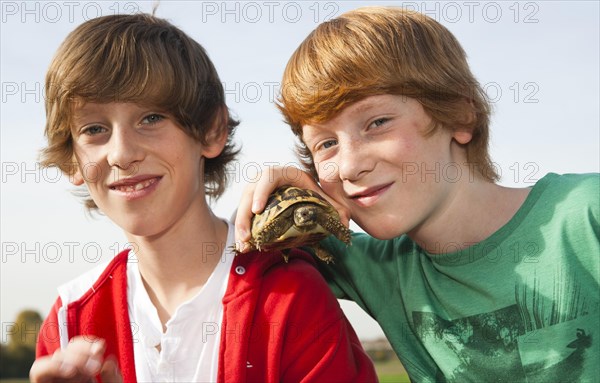 Two boys holding a turtle