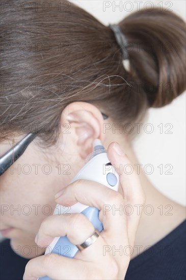 Woman using an ear thermometer