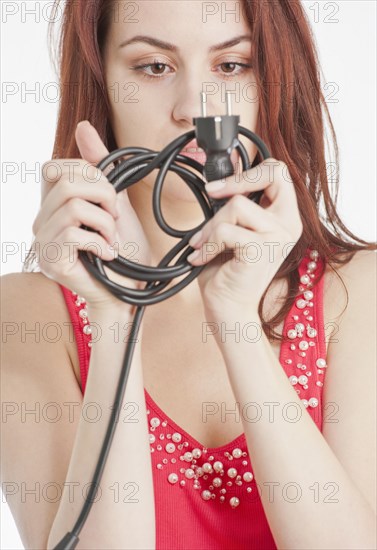 Young woman holding tangled electric cable