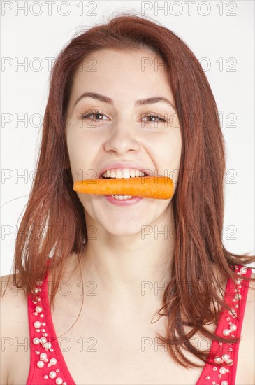Young woman biting on an organic carrot