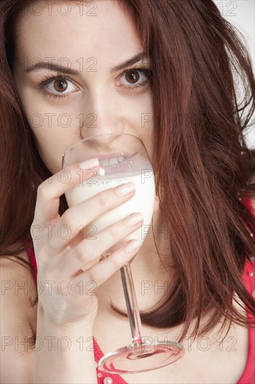 Young woman drinking milk from a wine glass