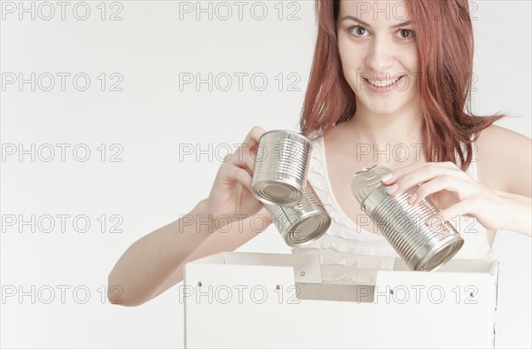 Young woman recycling tin cans