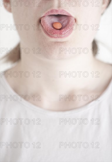 Woman with a pill on her tongue