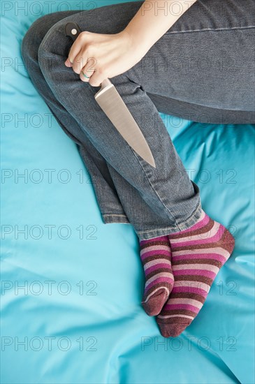 Woman lying down and holding a knife in a firm grip