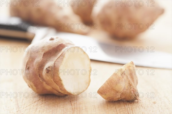 Raw Jerusalem artichokes (Helianthus tuberosus) and a knife on a cutting board