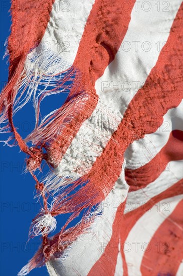 Torn American flag against blue sky