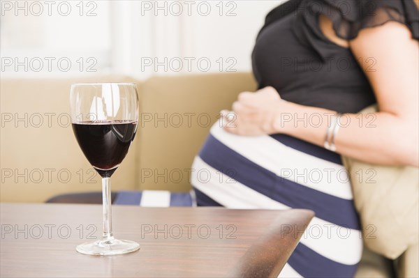 A glass of red wine and a pregnant woman