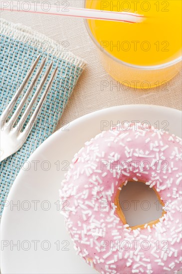 Donut with sprinkles and a glass of orange soda