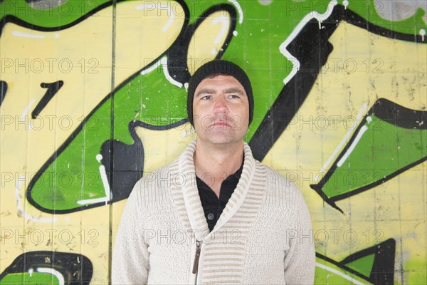 Man standing in front of wall covered with graffiti