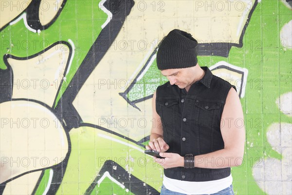 Man standing in front of wall covered with graffiti