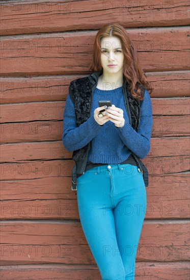 Beatiful young woman with red hair holding a mobile phone
