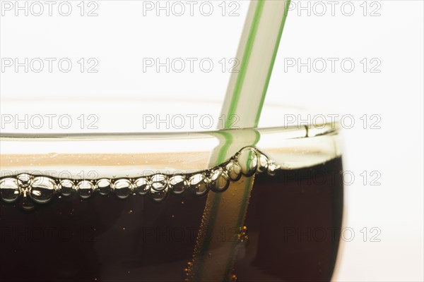 Closeup of a glass of cola with a drinking straw