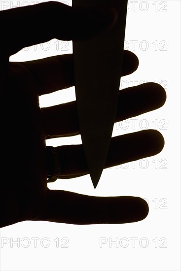 Violent scene with dagger pressed against fingers of a man's hand
