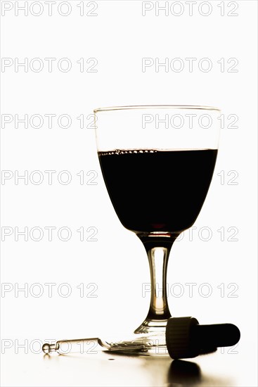 Pipette lying in front of glass filled with red wine