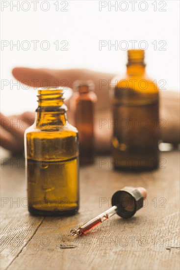 Medical bottles and pipette containing toxic fluid with hand of a victim of a crime in the back